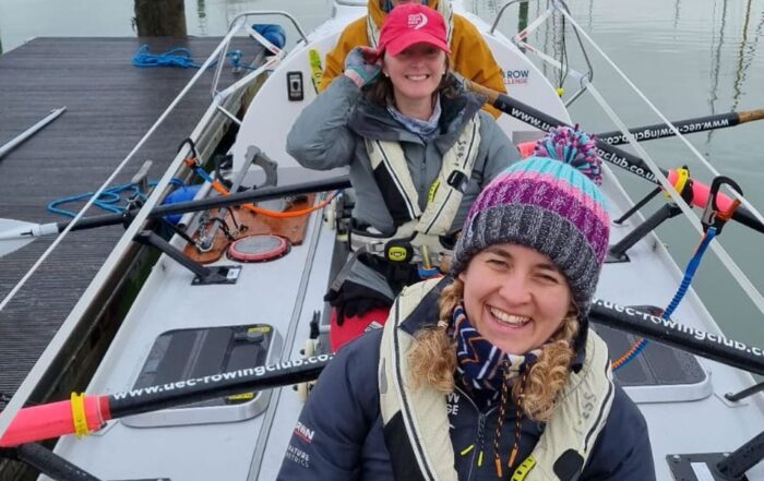 Three women on a rowing boat in a harbour before they set off on a training row